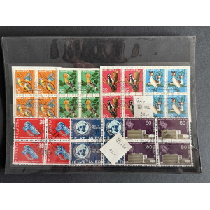 Sheet of colorful Helvetia postage stamps arranged in a grid, featuring orange and green bird stamps, red and blue designs, and some architectural illustrations on a dark display page.