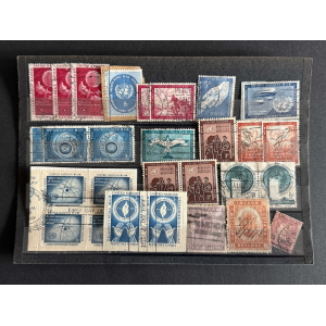 A page of colorful United Nations stamps arranged in rows on a black binder surface.