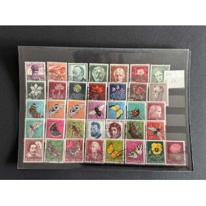 Sheet of colorful Swiss Pro Juventute stamps arranged in a grid, showing flowers, butterflies, and portraits on a dark page.