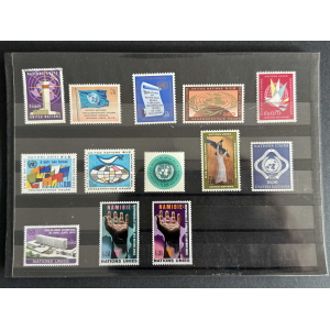Row of UN stamps on a black album page with colorful designs and multiple languages seen on each stamp.