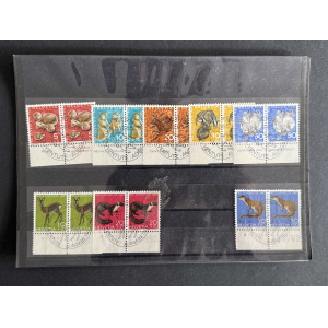 Row of colorful Swiss Pro Juventute stamps mounted on a black album page, each with animal illustrations and perforated edges. - or - Close-up of two rows of Pro Juventute stamps with bright backgrounds (red, blue, green, orange) and postmarks on a display page.