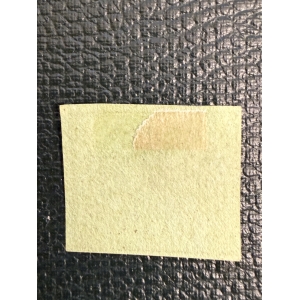 Blank yellow sticky note on a dark textured surface, with a small peeled corner revealing adhesive underneath.