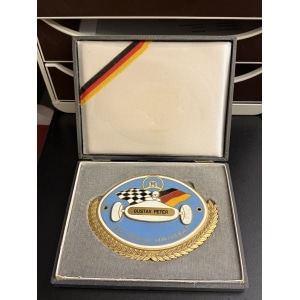 Enamel award medal in a presentation box: blue circle with a racing car, checkered flag, ‘GUSTAV PETER’, and ‘SCUDERIA HANSEAT’ inside a gold laurel wreath; ribbon with German colors is visible in the lid.